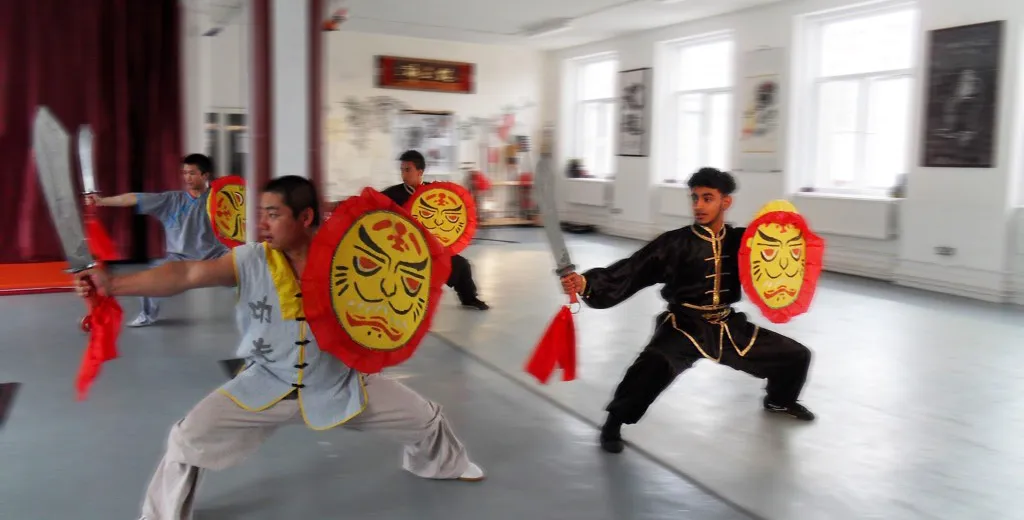 Three students follow direction from Shifu using on using the broadsward