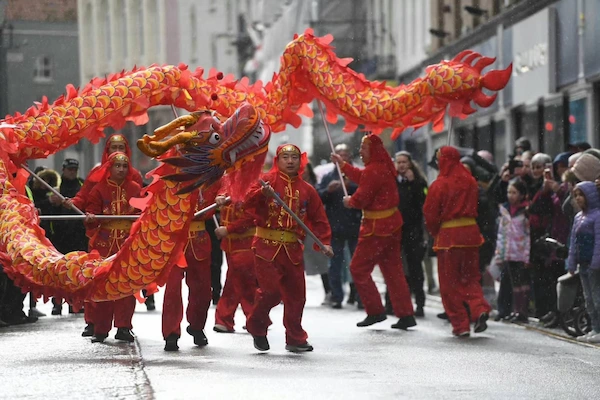 Seven Chinese Dragon dance performers holding dragon poles dance in the street