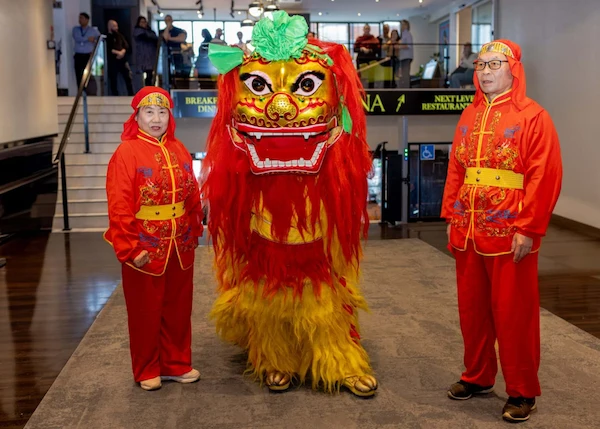 One Chinese Lion flanked by two performers dressed in traditional red costume