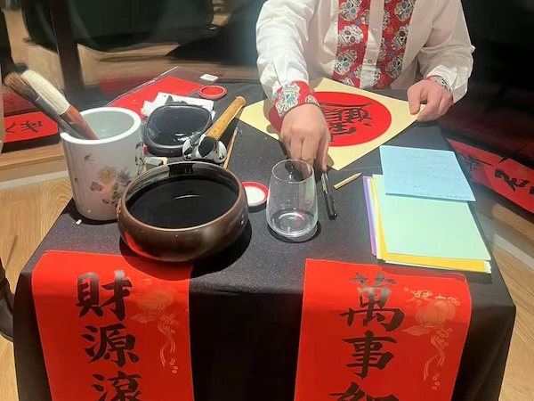 A calligrapher sitting at a table performing the art of calligraphy