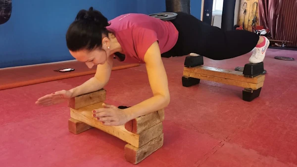 Student in a plack position on a raised surface and with weights on her back