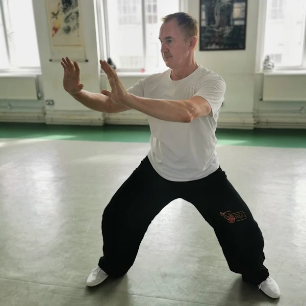 Student in a Tai Chi stance with both hands raised to one side with palms facing forward